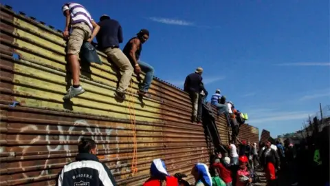 Reuters Migrants climb the border fence between Mexico and the United States