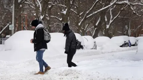 Getty Images People walk down a snow covered street