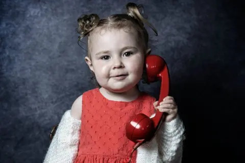 Debbie Todd A young girl holds a phone