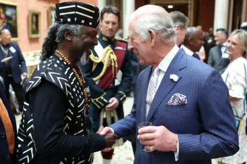 Getty Images King Charles shakes hands with a guest during a reception to mark the 75th anniversary of Windrush at Buckingham Palace on 14 June, 2023