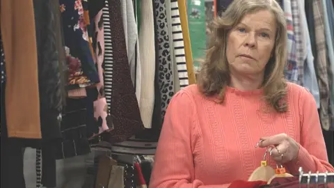 BBC Volunteer Debbie Russell holding hangers with donated items