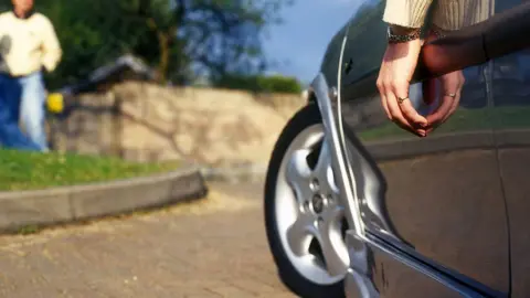 PYMCA/GETTY Hand hanging out of window of customised car