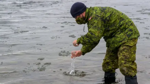 Courtesy Canadian Armed Forces A Canadian armed forces member collecting a water sample