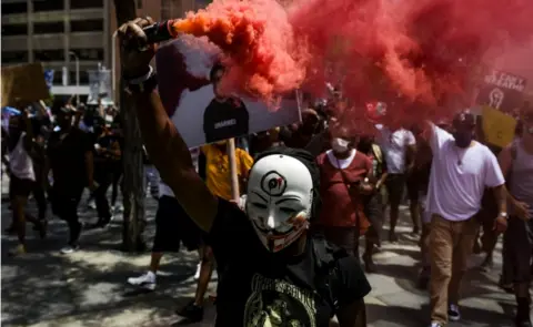 Getty Images A man holds a smoke grenade as thousands of people march in Denver, Colorado, 30 May 2020