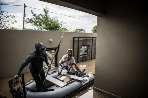 AFP Two men approach a house in a dinghy.