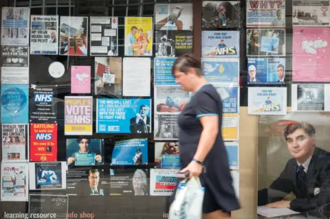 Getty Images A woman passes a photograph of founder of the National Health Service, Aneurin Bevan, displayed in a shop window in Tredegar in Wales