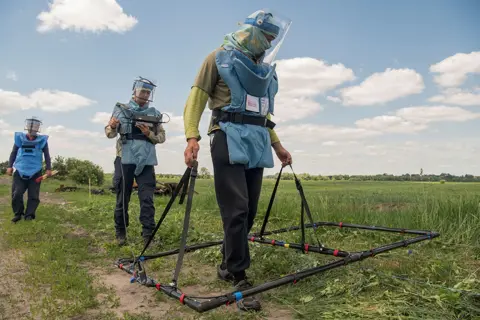 Vladyslav Musiienko / Reuters Deminers demonstrate searching for explosive devices using an Ebinger large loop metal detector, outside the town of Ichnia, Ukraine on 7 June 2022