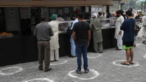 AFP Customers wait to buy food in Lahore, Pakistan