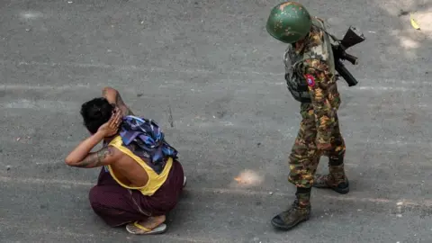 Getty Images A soldier stands next to a detained man during a demonstration against the military coup in Mandalay on March 3, 2021