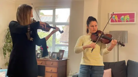 Kate Bradbrook/BBC Caroline Owen and Asya Bulchak playing violin