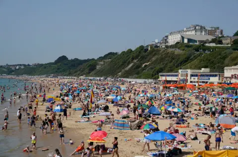 Andrew Matthews / PA People enjoy the warm weather on Bournemouth beach in Dorset.