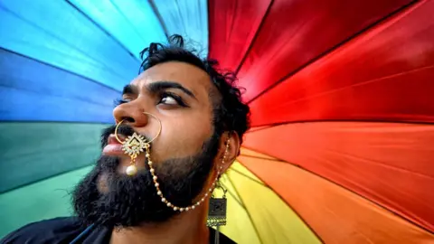 Getty Images A member of the LGBT community poses with a colourful umbrella before attending the Queer march in Kolkata, India in 2019.