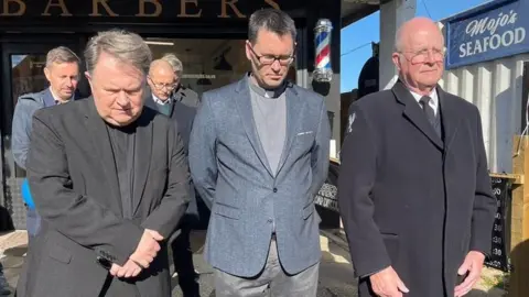 Jamie Niblock/BBC Father Jeffrey Woolnough, left, was among those observing the silence