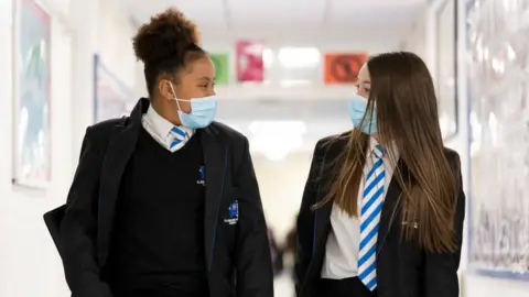 Getty Images Two girls wearing face masks walk down the corridor of Llanishen High School