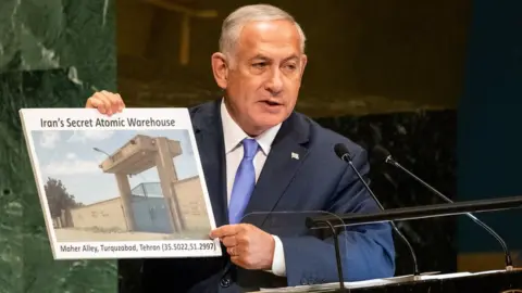 Getty Images Benjamin Netanyahu holds a picture of what he described as "Iran's secret atomic warehouse" in Tehran's Turquzabad district (27/09/18)