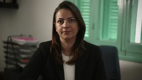 Lawyer and local politician Mine Atlı, pictured in front of a shuttered window with trays of documents behind her