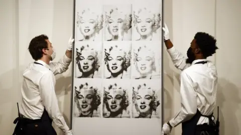 EPA Sotheby's employees hold US artist Andy Warhol"s 'Nine Marilyn's'