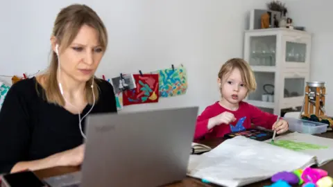 Getty Images A photographer's son paints while his mother works and attends a digital conference at home in Zehlendorf district during the second wave of the coronavirus pandemic on 18 February 2021 in Berlin, Germany