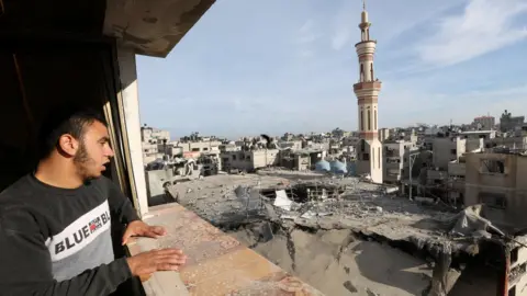 Reuters A Palestinian man looks at the remains of the al-Huda mosque in Rafah, in the southern Gaza Strip, which was reportedly destroyed in an Israeli strike during an operation to rescue hostages (12 February 2024)