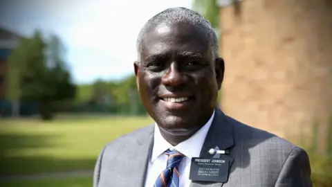 Elder Peter Johnson wearing a grey suit and a name badge