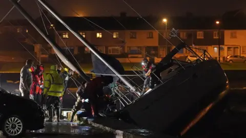 Niall Carson/PA Members of Irish Coast Guard inspect a boat that broke free from its birth and crashed into the harbour in Co. Waterford during Storm Betty