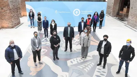 President Alberto Fernández together with other authorities and members of social organizations, posing forming an "X",