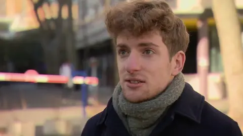 Still of Elliot Berke wearing a green scarf and blue coat