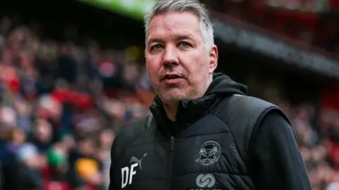 PA Media Darren Ferguson at a match with crowd behind him