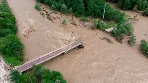 Getty Images A flooded river destroys a bridge in Ukraine, June 2020