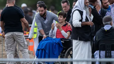 Getty Images Zaid Mustafa in a wheelchair at the funeral for his father and brother