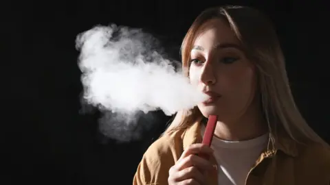 Getty Images A young woman using a disposable vape