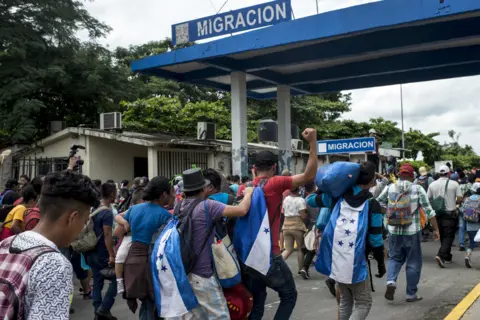 Encarni Pindado Thousands of Honduran migrants cross the border bridge between Guatemala and Mexico, while hundreds of federal police and soldiers wait on the other side.