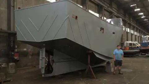 Guy Campbell/BBC Alex Wightman, aged 15, standing next to the ship's hull