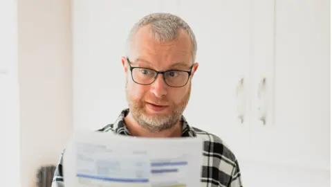 Getty Images Man looks at bill