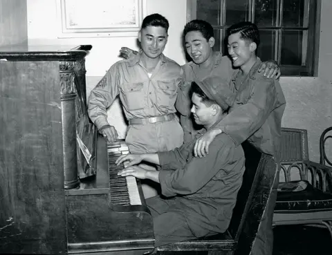 Getty Images A soldier plays an piano as soldiers sing along