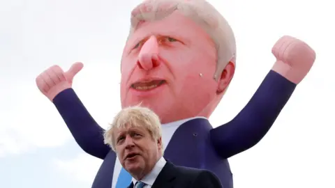 Reuters Prime Minister Boris Johnson with an inflatable figure depicting him in the background