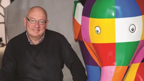 Adrian Rawlinson Terry Hunt with an Elmer sculpture