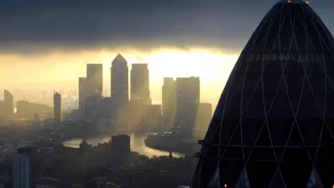 Press Association Canary Wharf seen at sunrise, behind the roof of The Gherkin