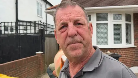 A man in a grey polo shirt stood in front of a cement mixer in Bromley.