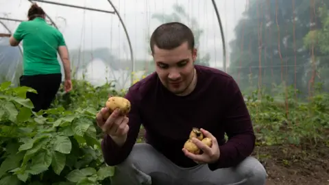 Nicole Mullan Photography’ Butterlope Farm student holding potatoes in a polytunnel