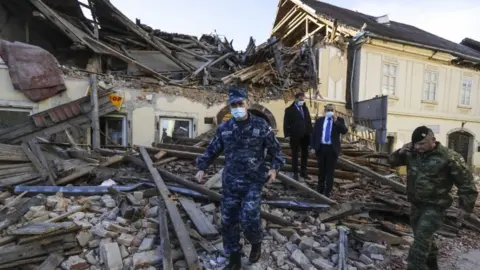 EPA Croatian soldiers and officials walk through the rubble from buildings damaged in an earthquake in Petrinja, Croatia, 29 December 2020