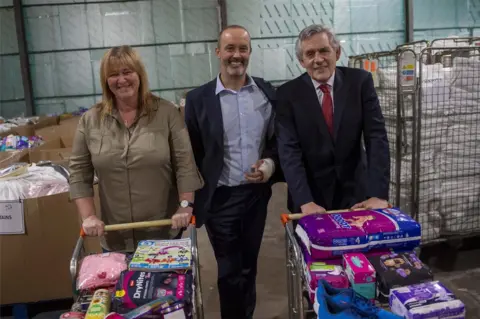 Amazon press Pauline Buchan, John Boumphrey and Gordon Brown at the Amazon warehouse in Lochgelly