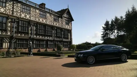 A mansion with a car parked in front