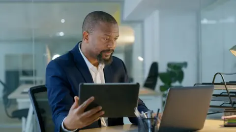 Getty Images A man looking at a screen and tablet