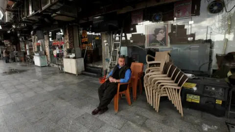 Reuters A Kurdish man sits near a closed cafe in Irbil (2 March 2020)