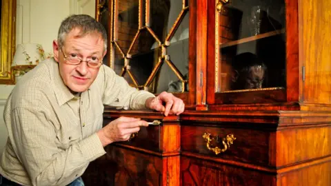 Dumfries House Conservation expert James Hardie working on the bookcase