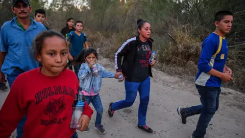 The Washington Post via Getty Images Border crossers quickly walk away after being discovered entering into the United States by the U.S. Border Patrol. The group had just rafted across the Rio Grande River in McAllen, Texas.