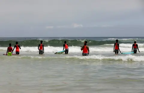 Zohra Bensemra / Reuters Khadjou Sambe teaches girls and women surfing techniques in the sea