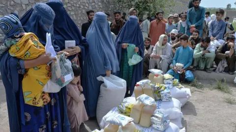 Getty Images Afghan women receive food donations as part of the World Food Programme (WFP) for displaced people, during the Islamic holy month of Ramadan in Jalalabad on April 20, 2021