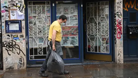 EPA Man walks past closed restaurant in Tower Hamlets, east London